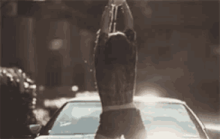 a woman is standing in front of a car with her arms up in the air