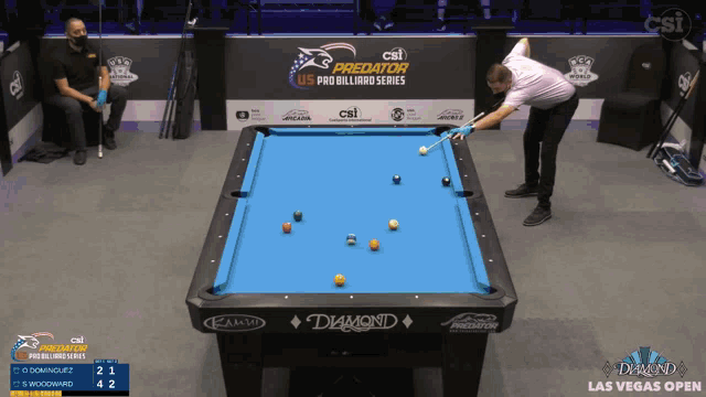 a man is playing pool in front of a csi predator us pro billiard series sign