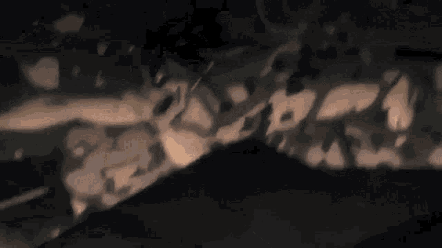 a person is laying on a bed in a dark room with smoke coming out of their mouth .