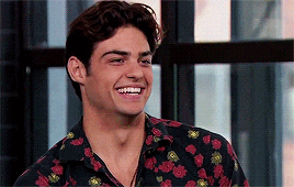 a young man wearing a floral shirt is smiling and looking at the camera .