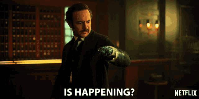 a man in a suit and tie is standing in a room with the words is happening on the bottom