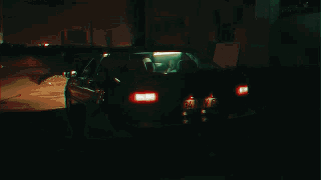 a car is driving down a road at night with a reflection of a police car in the rear view mirror