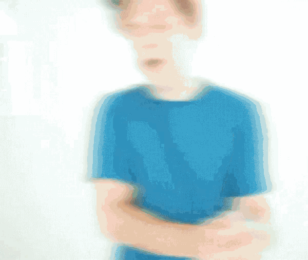 a young man wearing a blue shirt and a hat is making a funny face .
