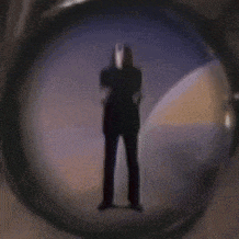 a silhouette of a man in a tuxedo is seen through a telescope lens