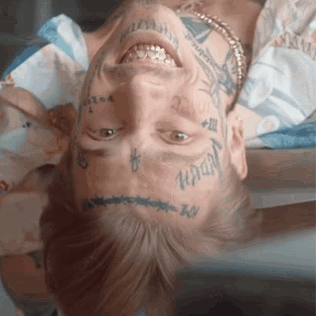 a man with a lot of tattoos on his face including one that says ' i am '