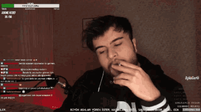 a man smoking a cigarette in front of a screen that says ' ler ' at the top