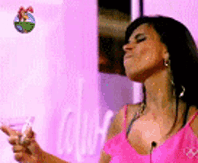a woman in a pink tank top is holding a white object in her hand .
