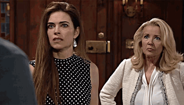 two women are standing next to each other in front of a door