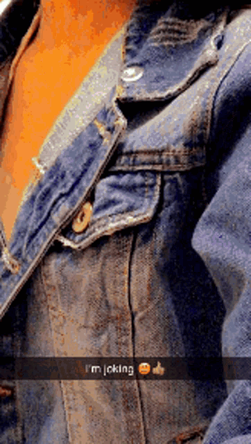 a close up of a person wearing a denim jacket with a snapchat caption that says i 'm joking
