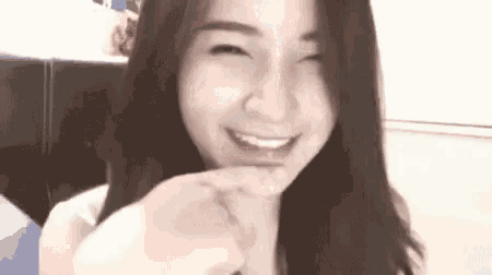 a woman with long hair is smiling and making a peace sign with her finger .