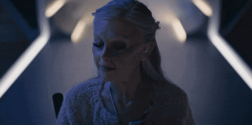 a woman in a white sweater is smiling in a dark hallway