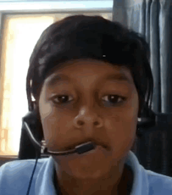 a young boy wearing a headset and a microphone in his mouth .