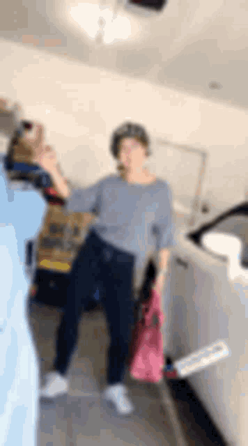 a woman is standing in a garage next to a white car .