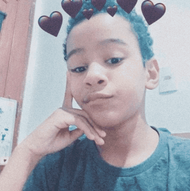 a young boy with hearts on his hair is taking a selfie .
