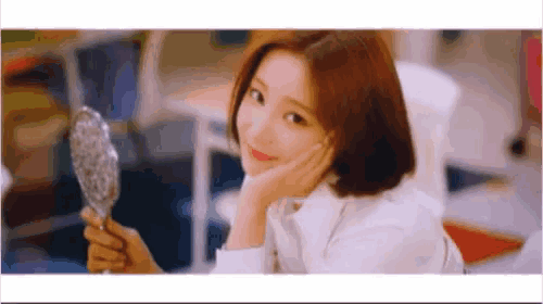 a woman is holding a mirror in her hand and smiling .