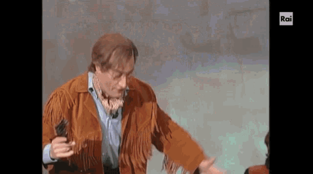 a man in a brown fringed jacket is holding a gun in his right hand and rai is displayed on the bottom of the screen