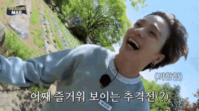 a man is laughing while wearing a blue sweater that says treasure map
