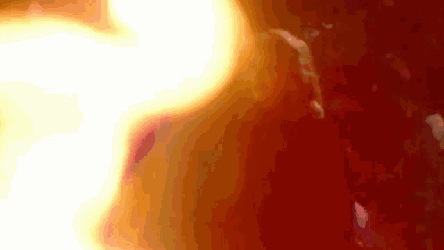 a close up of a red and yellow background with a flame coming out of it .