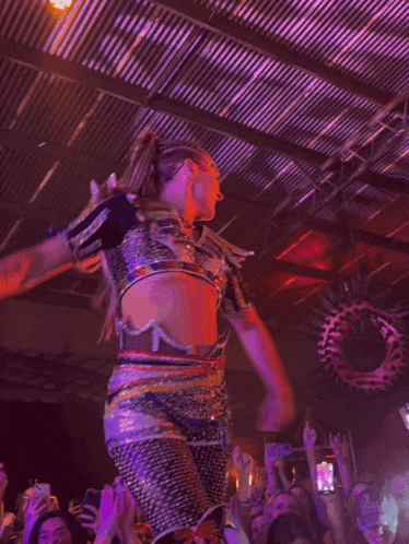 a woman in a purple outfit is dancing in front of a crowd of people