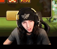 a man with long hair wearing headphones and a beanie with a zelda logo on it