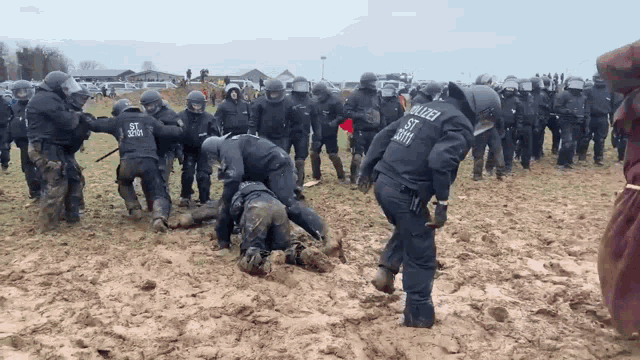 a group of police officers are standing in a muddy field and one of them is wearing a uniform that says polizei