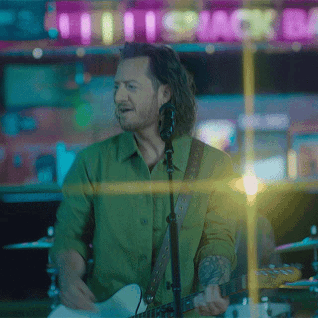 a man is singing into a microphone while playing a guitar