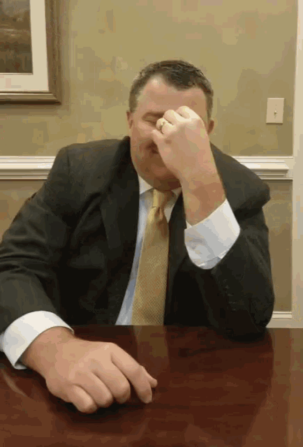 a man in a suit and tie is covering his face