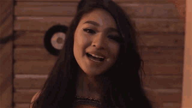 a close up of a woman 's face with a wooden wall in the background
