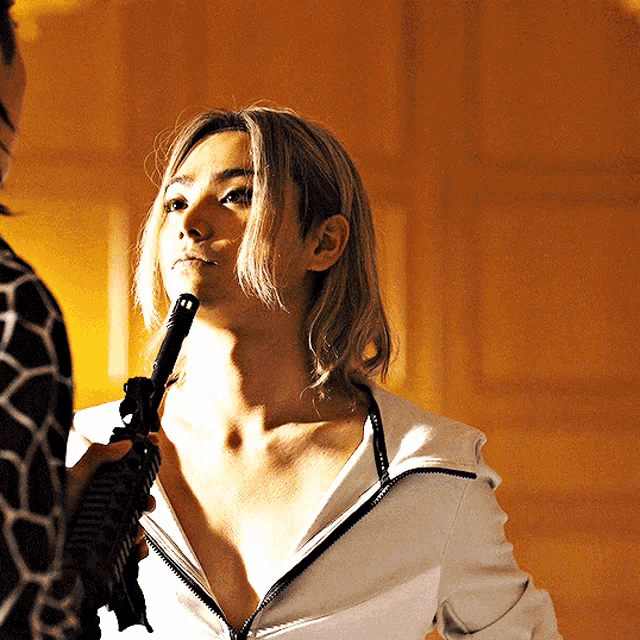 a woman holds a gun to her face while standing next to a man