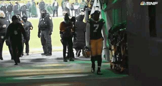 a football player with the number 7 on his jersey walks out of a locker room