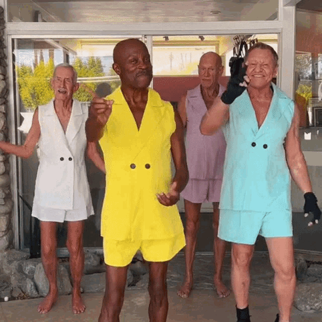 a group of men are standing in front of a glass door and one of them is wearing a yellow jacket