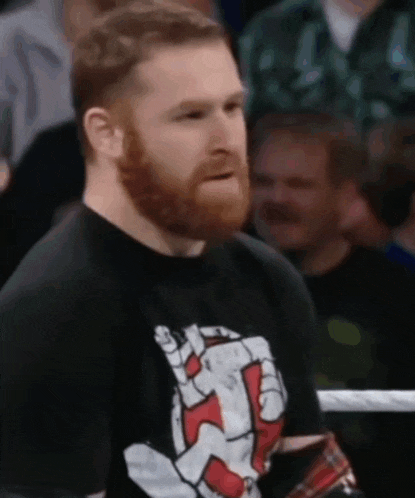 a man with a beard is wearing a black shirt with a hand on it