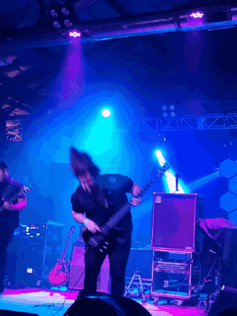 a man playing a guitar on a stage with purple lights behind him