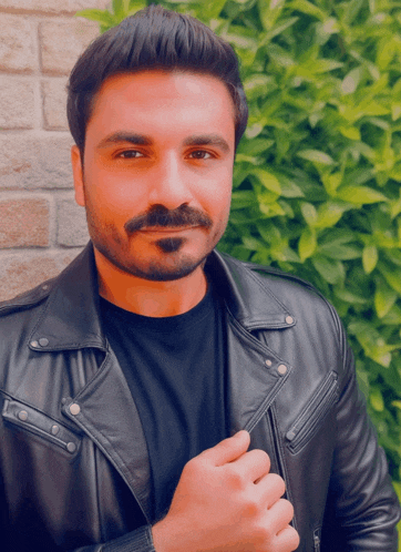 a man with a beard wearing a black shirt and a black leather jacket