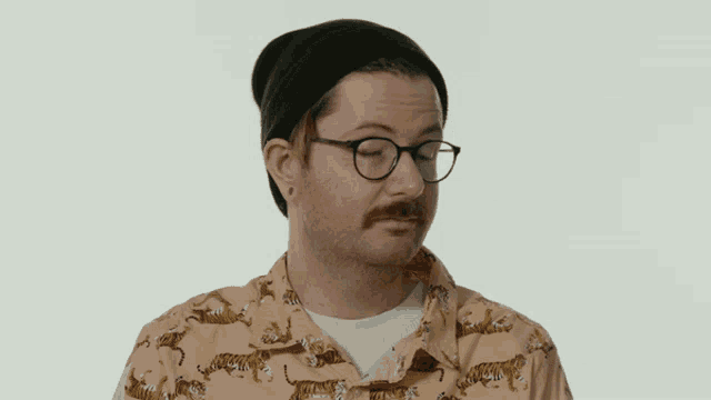 a man with glasses and a mustache says the word nice