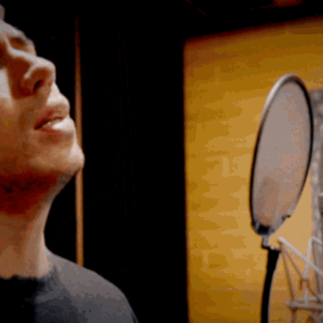 a man singing into a microphone with a yellow background