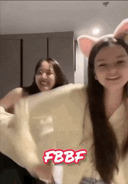two girls are dancing together in a room and one of them is wearing a cat headband .
