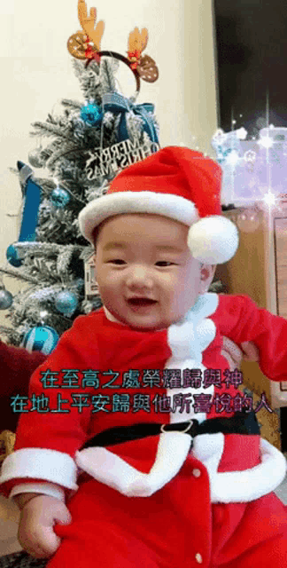 a baby dressed in a santa claus costume is smiling in front of a christmas tree