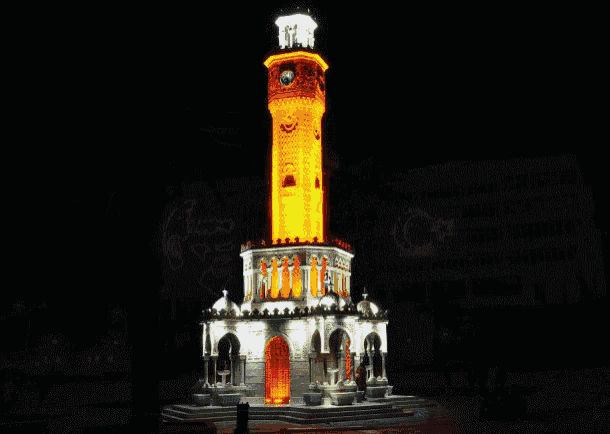 a clock tower is lit up at night and has a c on it