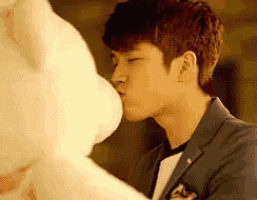 a man in a suit is kissing a white teddy bear