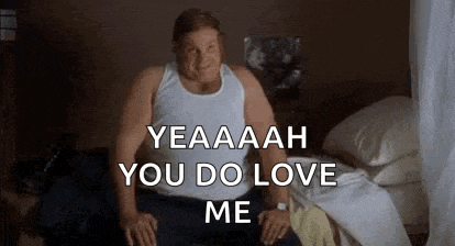 a man in a white tank top is sitting on a bed .