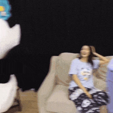 a woman sitting on a couch wearing a t-shirt that says ' snoopy ' on it