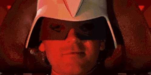 a person wearing a helmet and sunglasses is smiling in a dark room .