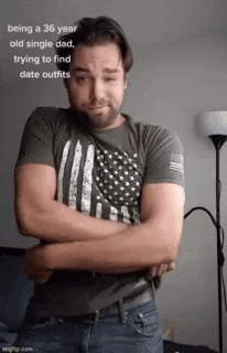 a man with his arms crossed is wearing an american flag shirt and jeans .