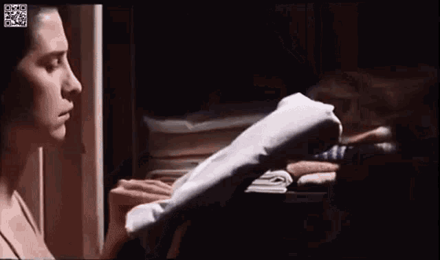 a woman is reading a book in a dark room while holding a piece of paper .
