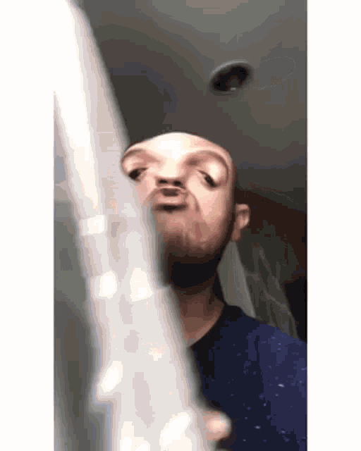 a bald man is making a funny face while holding a flute .