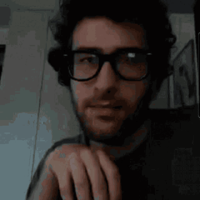 a man with glasses and a beard is making a face