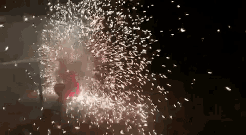 a person is standing in front of a fireworks display in the dark .