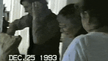a group of people standing in a room with the date dec 25 1993 on the screen