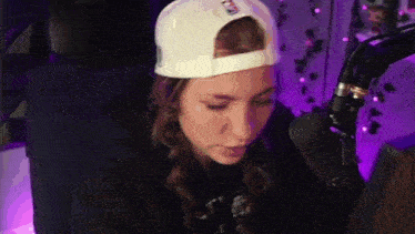 a woman is sitting in front of a microphone wearing a baseball cap .